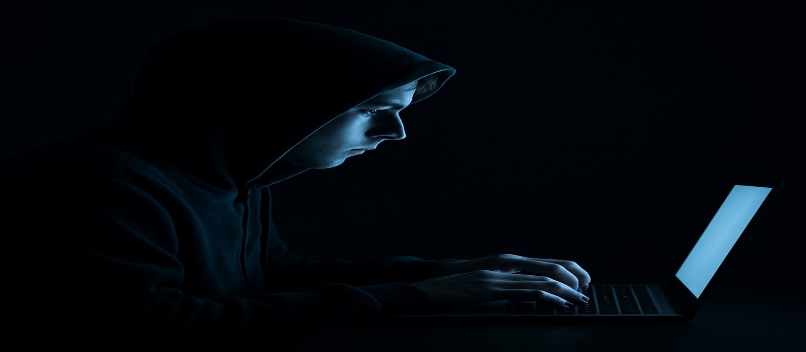 একজন ব্যক্তি অন্ধকারে ল্যাপটপে বসে মনোযোগী চেহারা নিয়ে lv18 ওয়েবসাইটে অনলাইন গেম کھیلছেন